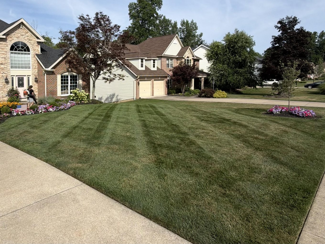 A freshly striped front lawn sweeping up to a brick and stone two-story home